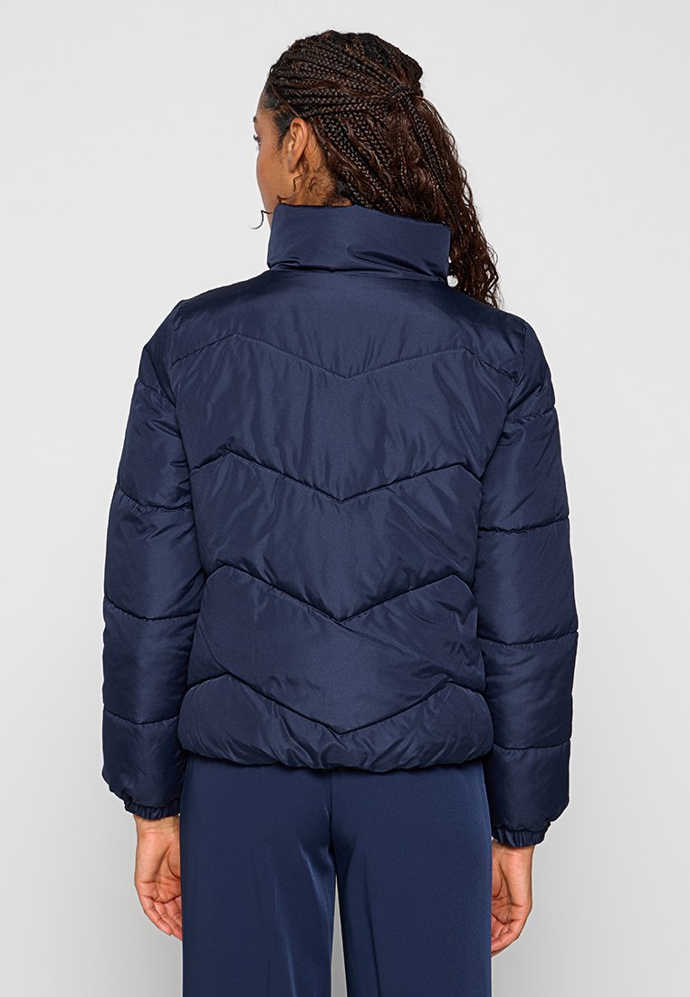 Marine pufferjack met hoge kraag, voorzien van chevronstiksels, elastische manchetten en een slim-fit tailleband. Lichtgewicht en geïsoleerd.