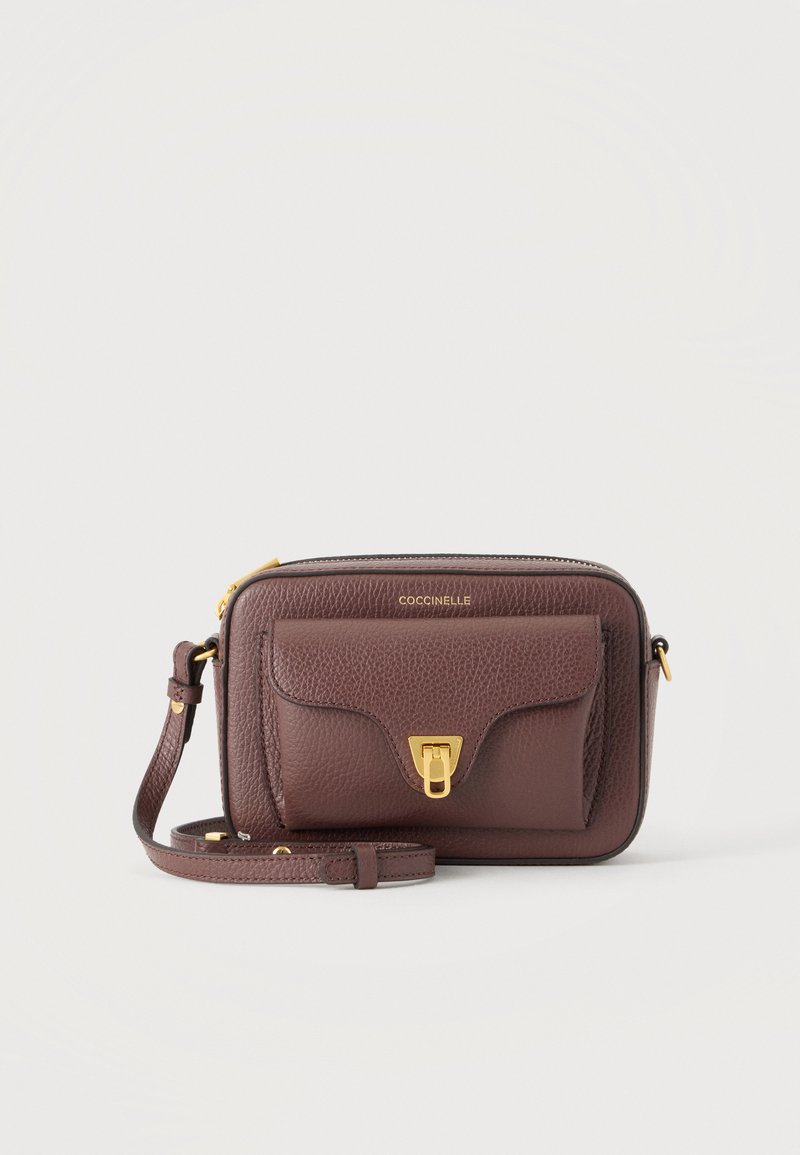 Καφέ δερμάτινη τσάντα crossbody με μπροστινή τσέπη με καπάκι, χρυσό κούμπωμα, λογότυπο επωνυμίας και ρυθμιζόμενο ιμάντα ώμου σε μονόχρωμο φόντο.