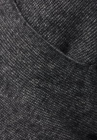 Gros plan sur un tissu texturé gris foncé avec un motif de tricot fin et un détail de couture diagonal.