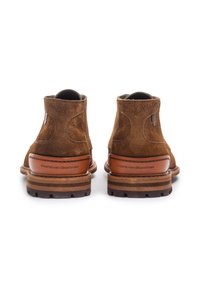 Braune Wildleder-Stiefeletten mit strukturiertem Finish, elastischen Seitenakzenten und einem hohen Lederabsatz mit einem Markenlogo.