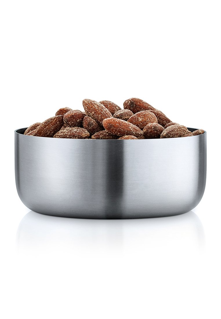 Edelstahl-Schüssel gefüllt mit ganzen gerösteten Mandeln, die mit Gewürzen überzogen sind, auf einer weißen reflektierenden Oberfläche.