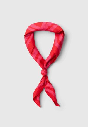 Roter und pink gestreifter Stoffschal, locker zu einem Knoten gebunden, auf einem schlichten hellgrauen Hintergrund.