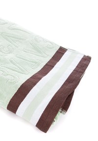 Toalla de color verde claro con textura en relieve, con franjas marrones y blancas en el borde. Material de algodón suave, forma rectangular.