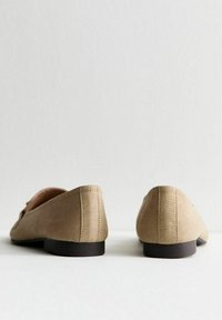 Ballerine in suede beige con tacco basso nero, dotate di una texture liscia e cuciture pulite. Il design sul retro è elegante e minimalista.