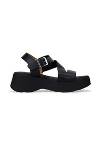 Sandalias de plataforma negras con tacón cuadrado, que presentan tiras cruzadas y una hebilla lateral. El material parece suave con un acabado mate.