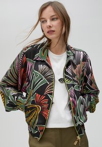 Višebojni bomber jakna s tropskim cvjetnim uzorkom na crnoj pozadini, sa zatvaranjem na munju i elastičnim manšetama.