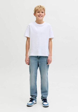 Balta īsroku T-krekls, gaiši zili džinsi no džinsa auduma un sporta apavi ar ziliem akcentiem. Vienkāršs dizains, vaļīgs piegriezums un ikdienas izskats.