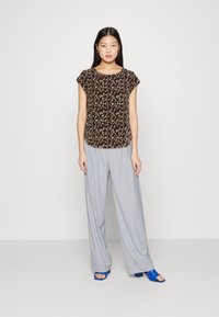 Musthavemustmustmustmustmustmustlight-grey wide-leg bottoms coupling teamed with rounded-neck short sleeved top adorned in bold floral designs, elevated by sophisticated blue-heeled sandals.