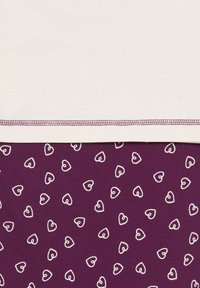 White top with purple bottom featuring a repeated pattern of small white hearts, finished with contrasting stitching at the seam.
