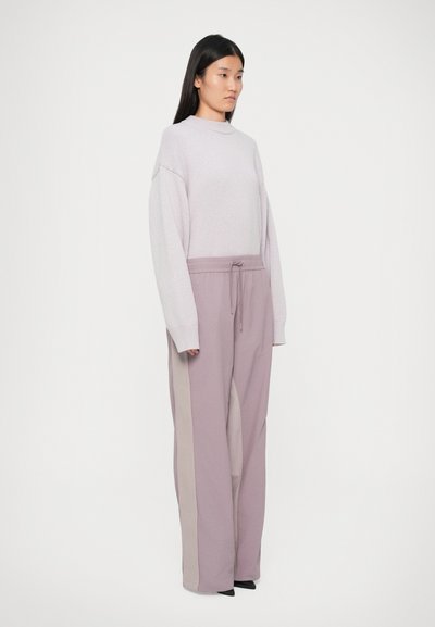 Sweater de malha lilás claro com ombros caídos e mangas longas, combinado com calças largas em lavanda com riscas laterais beges.