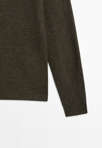 Tmavě hnědý pletený svetr s hladkou texturou, se dlouhými rukávy a kulatým výstřihem. Jednoduchý design s žebrovanými detaily na lemu.