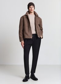 Giacca in pile marrone con collo a camicia, maglione lavorato a maglia color crema, pantaloni neri su misura e stivaletti in pelle nera. Design semplice e moderno.