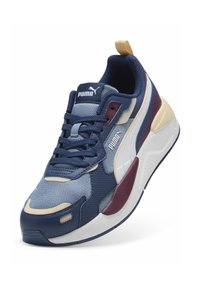 Baskets de sport bleu marine et crème avec des panneaux en mesh et en cuir, dotées d'une touche bordeaux, d'un col rembourré et d'une semelle blanche épaisse.