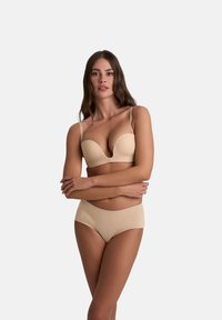 Beige gewatteerde bh met verstelbare bandjes en een diepe V-halslijn, vergezeld van naadloze beige high-waisted slipjes. Soepele textuur, minimaal ontwerp.