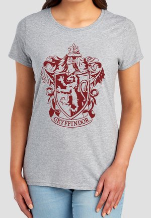 Woman wearing a gray T-shirt with a maroon Gryffindor lion crest and banner printed on the front.