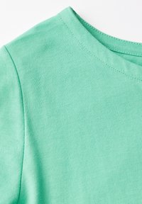 Mentolově zelené tričko s klasickým kulatým výstřihem, hladkou texturou a krátkými rukávy. Tkanina má jemný žebrovaný vzor.