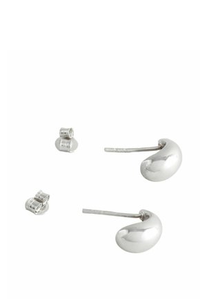 Silberne Ohrringe aus Metall in Form von Kidneybohnen mit einer polierten Oberfläche, begleitet von kleinen runden Steckerohrringen.