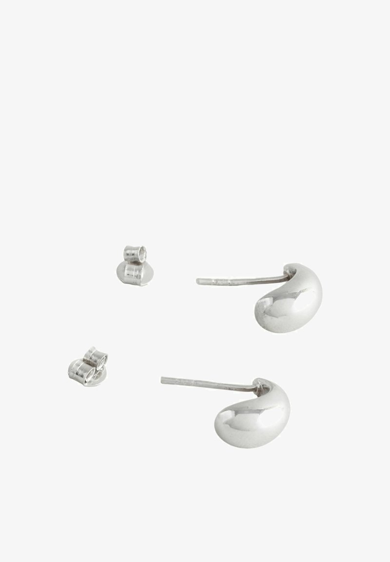 Boucles d'oreilles en métal argenté en forme de haricot, avec une finition polie, accompagnées de petites clous ronds.