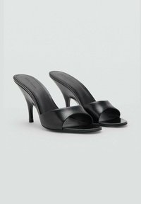 Mule aperti in pelle nera con una larga fascetta, tacco a stiletto e texture liscia. Design minimalista con una silhouette elegante.