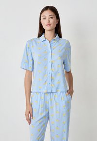 Lichtblauw set met kortekorte mouwen en broek, met een gestreept patroon en gele kersenmotieven. Gemaakt van een zachte, lichte stof.