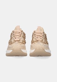Zapatillas deportivas beige con upper texturizado, costuras decorativas y acentos brillantes. Presentan una entresuela blanca y una suela de goma con un diseño.