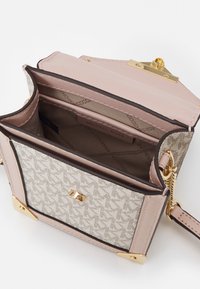 Torebka crossbody z beżowym wzorzonym płótnem na zewnątrz i jasnoróżowymi skórzanymi akcentami, złotymi elementami oraz przestronnym wnętrzem z przegrodami.