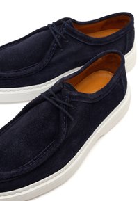 Navy blue suede lace-up casual shoes with white rubber soles and tan leather inner lining, angled view showing shoe details.