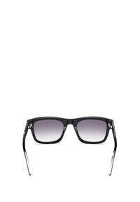Occhiali da sole con montatura nera quadrata, lenti a gradiente, punte delle aste in acetato trasparente e dettagli in argento vicino alle cerniere.