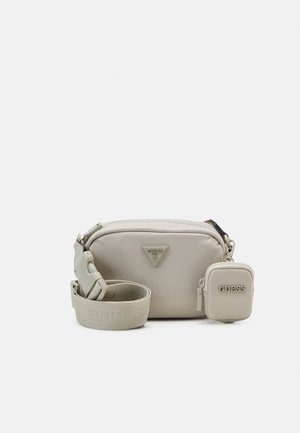 Beige crossbodytas met rits, driehoekig logo aan de voorkant, verstelbare band en klein aangehecht zakje met GUESS-logo.