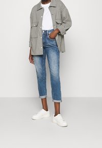 Svart och vit rutiga överdimensionerad jacka, vit t-shirt, urtvättade blå cropped jeans och vita sneakers. Jeansarna är uppvikta vid ankle.