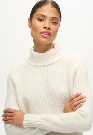 Maglioncino a coste color crema con collo alto, maniche lunghe e una texture morbida, caratterizzato da sottili linee verticali e una vestibilità rilassata.