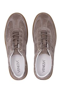 Paar taupe suède veterschoenen met witte stiksels en bruine rubberen zolen, gezien van bovenaf.