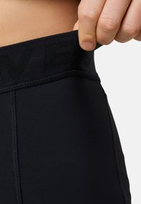 Leggings sportive neri con una larga vita texture. Il materiale sembra liscio con cuciture visibili lungo le giunture.