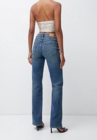 Jean bleu taille haute, coupe droite en denim avec un délavage léger. Comprend deux poches arrière et une étiquette en cuir sur la taille.