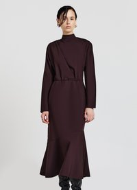 Langes braunes Kleid mit hohem Kragen, tailliertem Schnitt, langen Ärmeln und ausgestellt geschnittenem Saum. Hergestellt aus einem glatten, strukturierten Stoff mit kantigen Nähten.