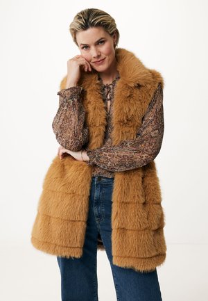 Neppelsen vest in warm bruin met een gelaagd ontwerp en een brede kraag. Een gebloemde blouse eronder en denim jeans maken de outfit compleet.