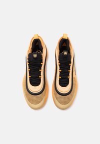 Scarpe sportive con una tomaia nera, dettagli arancioni e un design in rete testurizzata. La suola è di un colore chiaro a contrasto con una forma arrotondata.