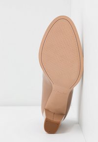 Bottine en cuir brun affichant un dessus lisse, un bout pointu et une semelle en caoutchouc robuste avec un motif texturé pour une meilleure adhérence.