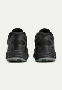 Black athletic shoes with a textured surface, cushioned heel, and distinctive pattern on the back. Rubber sole with a slight translucent grip.