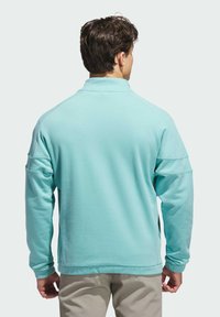 Sudadera azul claro con cuello alto, mangas largas y aberturas laterales, que presenta un tejido suave y texturizado y puños acanalados.