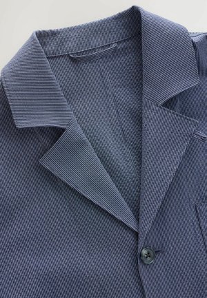 Marineblauwe en witte gestreepte blazer met een notch-kraag, enkele knoopsluiting en textuurstof. Heeft een borstzak en revers.