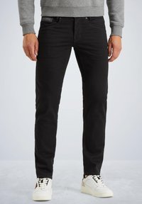 Čierne denimové džínsy so slim fit strihom, dizajnom s piatimi vreckami a jemným prešívaním. Skombinované s bielymi teniskami.