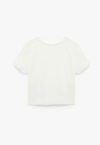 Hvid cropped t-shirt med korte ærmer, rund halsudskæring og et enkelt design. Blød tekstur uden synlige mønstre eller detaljer.