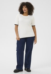 Witte geribde short-sleeve top met zwarte rand, gecombineerd met recht gesneden donkerblauwe spijkerbroeken en zwarte plateau schoenen. Eenvoudig ontwerp.