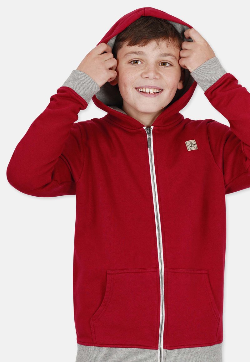 Red zip-up hoodie with a gray inner lining and cuffs, featuring two front pockets and a small logo patch on the chest. Soft fabric texture.
