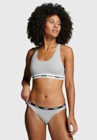 Grauer Sport-BH mit einem schwarz-weißen Puma-Logo-Band; passender grauer String mit schwarzem Band. Weicher, dehnbarer Stoff, minimalistisches Design.