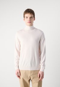 Pull col roulé rose clair à manches longues, fabriqué dans un matériau lisse et doux. Présente un design ajusté et des poignets et un ourlet côtelés.