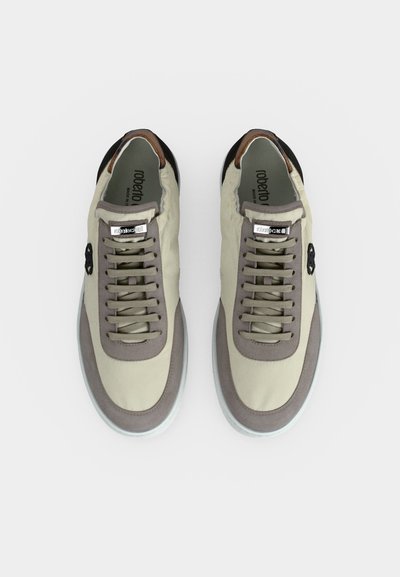 Ζευγάρι μπεζ και γκρι χαμηλά sneakers με κορδόνια, μαύρες λεπτομέρειες και σήμανση στη γλώσσα και στις εσωτερικές σόλες σε λευκό φόντο.