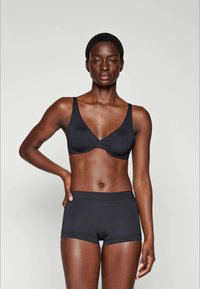 Black seamless bra with a low-V neckline and wide straps, paired with matching black boyshorts featuring a soft elastic waistband.