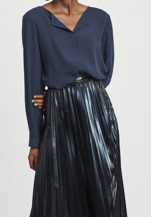Blusa blu navy con scollatura a V e maniche lunghe abbinata a una gonna nera metallici plissettata a vita alta, che mette in risalto una finitura lucida.